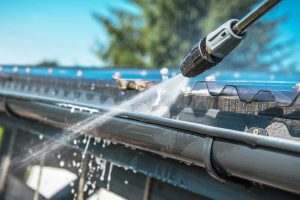 Cleaning a roof gutter with a pressure washer