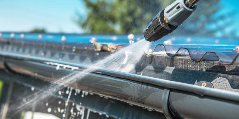 Cleaning a roof gutter with a pressure washer